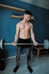 Fototapeta na wymiar handsome bearded guy exercising with barbell at home