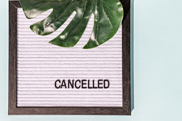 A message Board with the words canceled and a monstera leaf on a blue background.Concept pandemic coronavirus and the global crisis