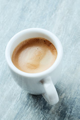 Cup of coffee on bright wooden background.