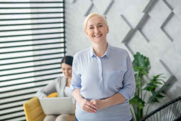 Fototapeta premium Adult smiling blonde woman standing in room.