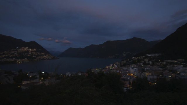 Fast pan over the city of lugano in the evening with monte bre, lake lugano, paradiso and monte san salvatore in the background