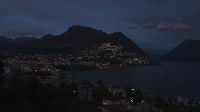 Slow pan over the city of lugano in the evening with monte bre, lake lugano, paradiso and monte san salvatore in the background