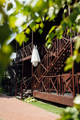 Elegant wedding dress hanging on a wooden railing outside