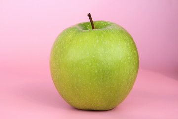Green yellow apple on a pink background. Juicy ripe beautiful fruit.