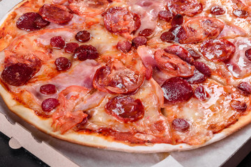 Pepperoni pizza with mozzarella cheese, salami, tomatoes, pepper and spices
