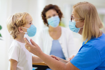 Doctor examining sick child in face mask