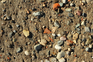 Small stones and sand. The natural texture of the soil. Shore of a reservoir with a beach and pebbles.
