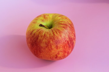 Red yellow apple on a pink background. Juicy ripe beautiful fruit.