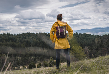 Woman in yellow raincoat hiking in nature