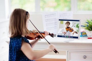 Child playing violin. Remote learning.