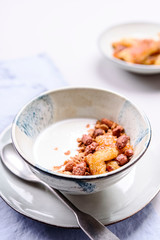 Healthy breakfast yogurt bowl with granola and caramelized bananas and nuts on grey concrete background. Selective focus