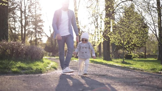 Adorable little gilr spend time with her father. Dad and daughter walk in the park. Stylish family. Happy little girl in sunglasses