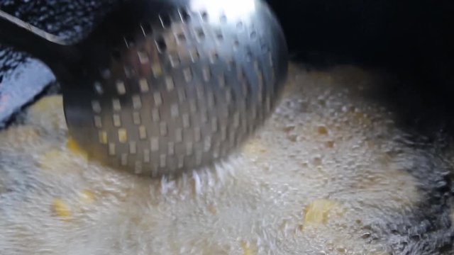 a closeup frying plantains in boiling oil. delicious tropical snack cooked in a traditional way. healthy vegetarian and natural food. Bananas cut into slices to make plantain chips.