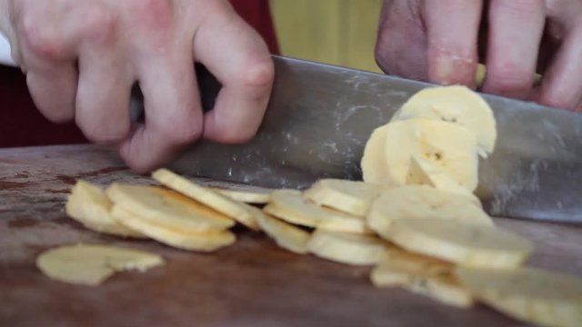 cutting delicious banana in a rustic way in slices on a cutting board to make fried plantains. 
cooking bananas