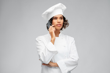 cooking, culinary and people concept - female chef in toque calling on smartphone over grey background
