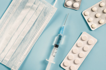 Medical mask, medicine, tablets, injection syringe on a blue background.