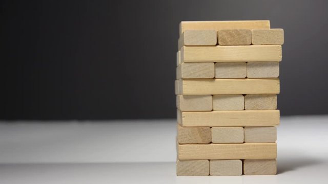 Close up hand holding blocks wood game jenga isolated on white background.