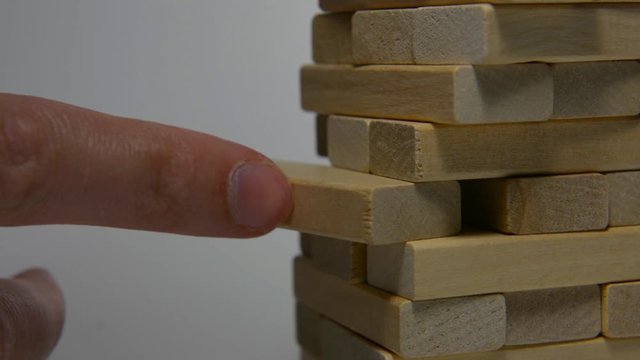 Close up hand holding blocks wood game jenga isolated on white background.