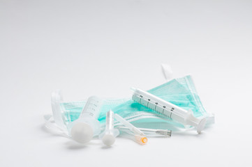 Green protective mmedical, surgical face masc COVID-19. on white background with syringes and needles