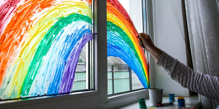 hand painting rainbow on a window, stay home during quarantine