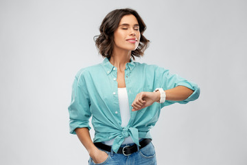 people concept - portrait of happy smiling young woman in turquoise shirt with smart watch...