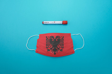 Disposable medical surgical face mask with Albania flag superimposed on it with positive COVID-19...
