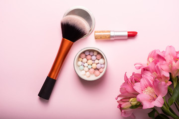 Obraz na płótnie Canvas Make-up powder brush, powder in balls, red lipstick and beautiful pink bouquet of flowers. Womens make-up kit, gift for girl concept