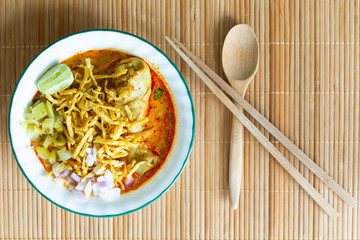 Northern Thai food (Khao Soi), spicy curry noodles soup with coconut milk and chicken on bamboo mat, Top view