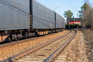Train in a curve with a red house in the direction of the railway track