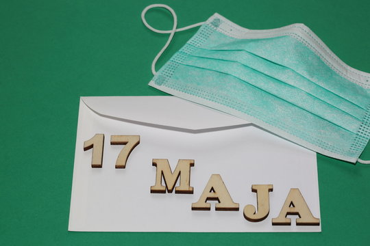 nvelope with date 17 MAY in Polish language, face protect disposable mask on it, green background close up, cocnept of possible  correspondence voting in Poland