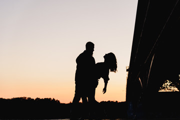 Fototapeta na wymiar Silhouette of a couple in love at sunset in the city landscape.
