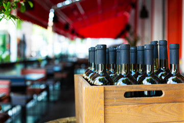 A wooden box filled with bottles of wine. Bank party celebration in an open-air restaurant