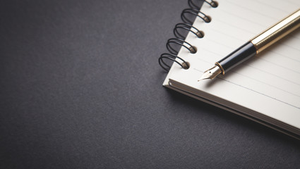 Pen and notepad on black background.