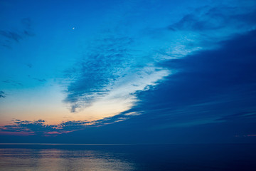 Beautiful scenery of Baltic sea. Cloudy weather. Soft focus of the sea. Moon in the night sky.