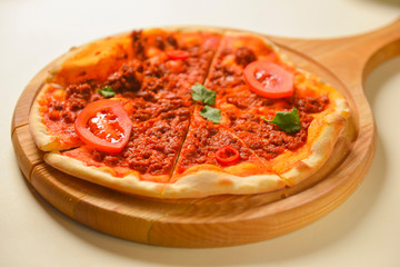 Traditional italian food. Delicious fresh pizza with bolognese sauce, tomatoes, pepper on wooden board, flat lay.