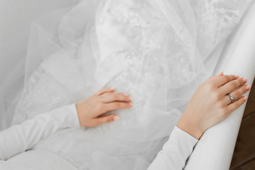 Obraz premium hands on the dress of the bride,close-up of the hands of a bride lying in the bathroom,wedding ring with white gold on the bride’s finger,wedding details,hands on a snow-white wedding dress