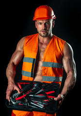 Male sexy builder in hardhat. Portrait of muscular man in standing on black background. Industrial...