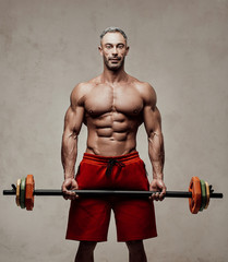 Healthy and energetic man doing doing a biceps exercise with a barbell, focused and looking strong © Fxquadro