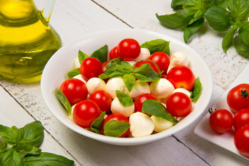 Caprese salad on a white wooden table with ingredients. Selected focus.