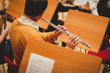 A man plays the flute in a big  symphony orchestra. A man plays fly. Rehearsal.