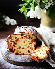 Curd cake with raisins on a cutting board on a dark background with lilac flowers
