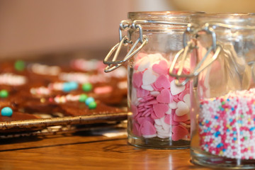 Sugar sprinkles in jars in front of cookies