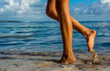 Woman legs walking on the beach