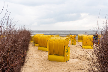 Obraz premium Sandy beach and typical hooded beach chairs in Cuxhaven in the North Sea coast a cloudy day of Summer. Germany
