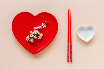 Spring floral Japanese food concept with blooming cherry tree branches and serving with red heart...
