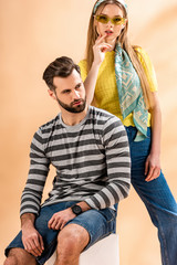 Obraz premium young fashionable couple posing in summer clothes on white cube on beige