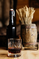 dark bottle with a glass of whiskey on a wall background