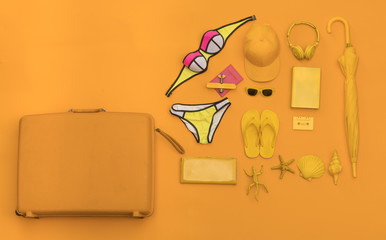 yellow holiday vacation suitcase and beach accessories on a yellow background