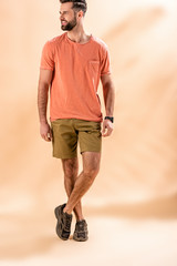 cheerful stylish man posing in shorts and summer t-shirt on beige