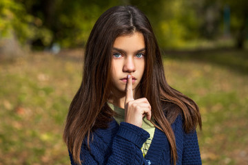 Naklejka premium Pretty brunette little girl posing in autumn park background